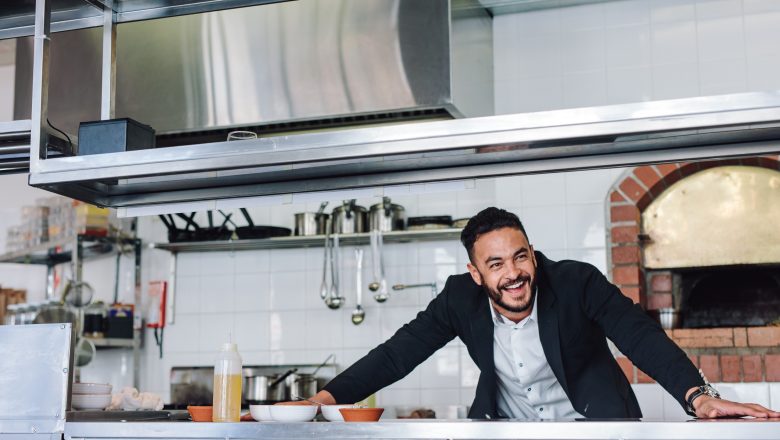 Smiling restaurant owner standing at kitchen counter